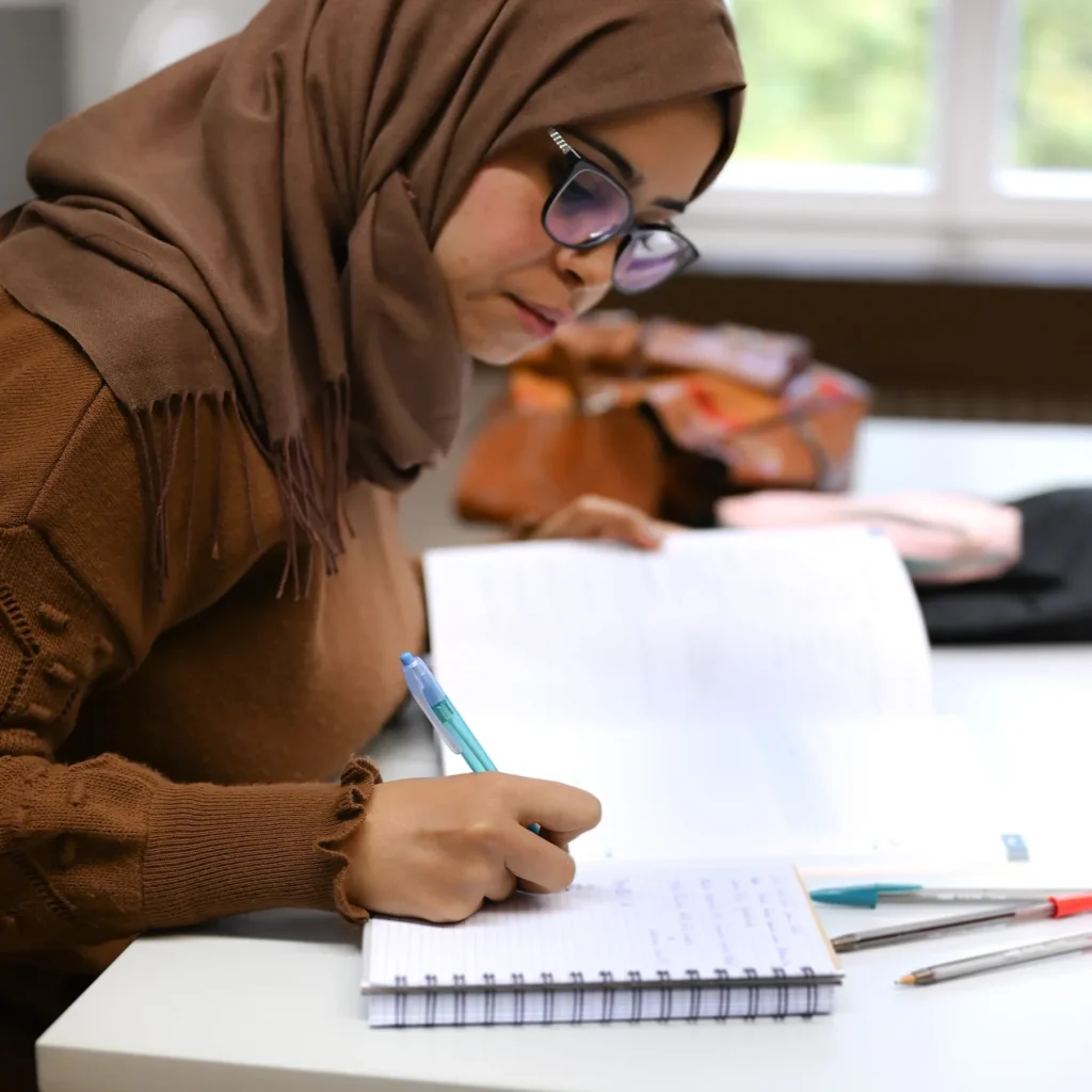 Teilnehmerin schreibt Notizen im Deutsch- und Integrationskurs bei LECTOR in Saarbrücken